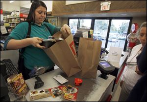 Cashier Denise Cruz checks out customers' purchases at a hardware store in Los Angeles Tuesday, Oct. 4, 2011.   Service firms that employ 90 percent of the U.S. work force grew at a slower pace in September, evidence that the economy is growing but at a sluggish pace.