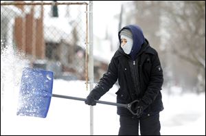 Paul Espino, 11, bundles up to shovel the walkway at his home on the corner of Jay and Clark in east Toledo in this Feb. 1, 2011, file photo.