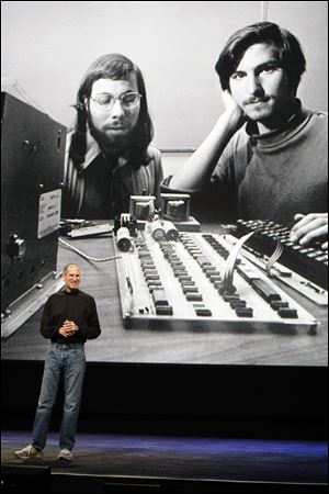 Then Apple CEO Steve Jobs stands in front of a photo of himself, right, and Steve Wozniak, left,  during an Apple event Jan. 27, 2010, in San Francisco. 