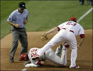 Philadelphia Phillies' Chase Utley (26) is tagged out at third by St. Louis Cardinals third baseman David Freese (23) as third base umpire Chris Guccione looks on during the sixth inning of Game 4 of baseball's National League division series on Wednesday, Oct. 5, 2011, in St. Louis.
