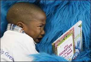 Despite his tears, Damorion Jones, 4, shares a hug with a book-holding Cookie Monster.