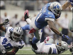 Detroit Lions wide receiver Calvin Johnson is tackled by Dallas Cowboys defensive back Danny McCray, left, and cornerback Terence Newman, right during the second half of an NFL football game Sunday, Oct. 2, 2011, in Arlington, Texas. The Lions won 34-30.