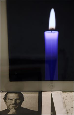 An iPad displays a candle besides a picture of Apple founder and former CEO Steve Jobs as a memorial tribute at an Apple retail store in Hong Kong on Thursday.