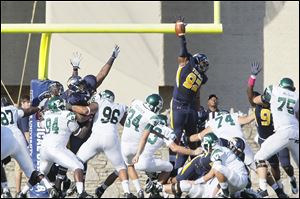 University of Toledo player Danny Farr, 92, blocks a PAT attempt by Eastern Michigan University kicker Kody Fulkerson during the second quarter at the Glass Bowl, Saturday.