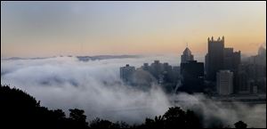 Fog prepares to roll over the Golden Triangle of Pittsburgh at sunrise, Friday .