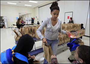 Eighth-grader Kya Mabrey hands out bags of food to kindergartners as Spring Elementary students receive a brown bag full of food for the weekend, Friday.