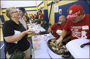 Judy Pelton and her husband, Jim, receive a portion of TnT Kielbasa from cook-off competitors Gus Franks and Tom Bibish on Saturday at Blessed Sacrament Church in Toledo. Twelve entrants competed in the Polish American Community of Toledo's second annual Kielbasa Cook-Off.