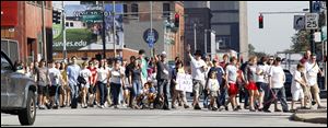 A crowd crosses Washington Street during the 1Mile Matters Walk. The walk ended at the 1Rocks-1Matters concert at Erie Street Market hall to raise money and awareness of the homeless.