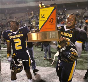 The Peace Pipe Trophy will be permanently housed at the University of Toledo, as they won it in 2010. UT's Taikwon Paige (2) and Archie Donald (42) celebrate the 2010 win at the Glass Bowl with the retired award.