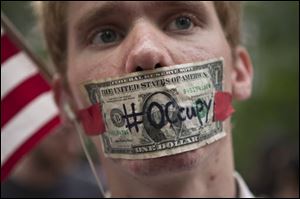 A protester affiliated with the Occupy Wall Street protests stands with a US dollar bill taped over his mouth in Zuccotti Park in New York.
