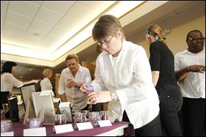 Marce Dupay, center, lights a candle in memory of  Brenda Gould, 46, who was murdered by her husband, at the service for northwest Ohio victims of domestic violence.