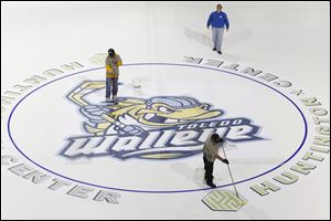 Workers finish putting down the logo at center ice to get the Huntington Center ready for its third season of Walleye Hockey. The arena's capacity is 7,431.