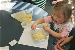 Zoe Dusseau, 3, of Temperance, works on her applesauce cake with crumble toppings during the story hour at the Bedford Branch Library. 