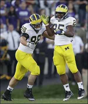 With defensive end Craig Roh, left, Michigan linebacker Kenny Demens celebrates sacking Northwestern quarterback  Dan Persa on Saturday.