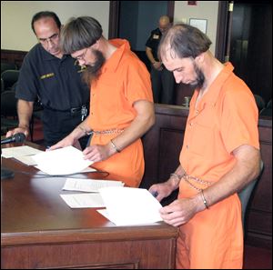 Jefferson County Sheriff Fred Abdalla, left, looks on as Lester Mullet, 26, center, and his brother Johnny Mullet, 38, review papers during a hearing in Steubenville, Ohio.