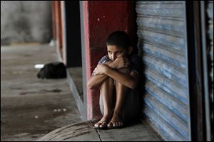 A boy takes shelter from rain Tuesday in front of a store at the harbor in Manzanillo, Mexico.