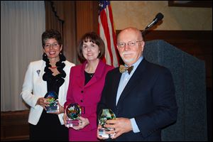 Judy Seibenick of Hospice of Northwest Ohio, left, Courtney Weiss of Unison Behavioral Health Group, and Jim Funk of Read for Literacy hold glass art their organizations received at the Northwest Ohio Innovation and Excellence Awards. The honors were presented yesterday. 