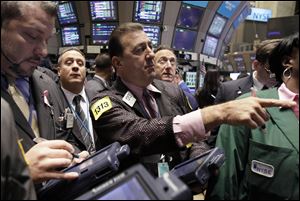 Stephen Holden, center, works on the floor of the New York Stock Exchange with fellow traders Wednesday.