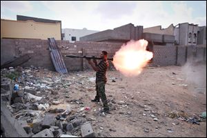 A revolutionary fighter fires a rocket-propelled grenade at Gadhafi loyalists in downtown Sirte, Libya.