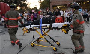 Rossford firefighters Dan Dorner, left, and Derek Smith transport a mock victim on a cot to a triage area during the Rossford Fire and Rescue Department's open house.