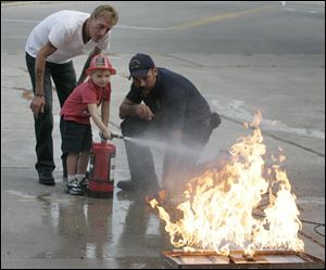 Duane LaHote, left, watches his son, Camron LaHote, 4, of Delta, use a fire extinguisher.