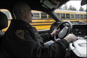 Sgt. Brian Foltz, with the Ohio Highway Patrol, looks for drivers violating school bus traffic laws near the Sylvania Whiteford Elementary School on Tuesday.