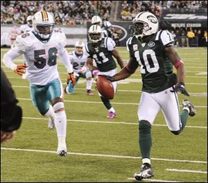 Jets wide receiver Santonio Holmes (10) runs past the Dolphins' Kevin Burnett (56) on his way to a touchdown during the fourth quarter.