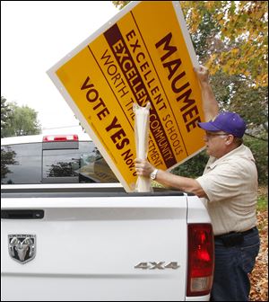 Maumee High School principal Larry Caffro spends the evening posting levy signs around Maumee in support of the school levy.