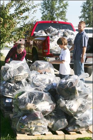 Hannah Jacobs, Erek Hansen, and Brad Fields load shoes at the Owens campus into the truck. Owens Environmental Club collected shoes to aid Erek in his goal of promoting environmental conservation and awareness. 