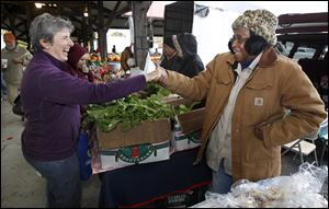 Katie Thomas talks to a customer at the Toledo Farmers' Market on Saturday.