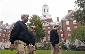 Harvard University student ROTC midshipmen Evan Roth, from left, Colin Dickinson and Catherine Philbin walk past Dunster House on the campus of Harvard University in Cambridge, Mass.