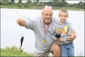 Ken Drew helps Noah Trapp, 5, at the Fishing for the Future fishing derby at Lake Mottram in Fostoria in September 2011. Drew, owner of Fostoria Bait & Tackle, sponsored the event as a way to get youth involved in fishing. He died later that night in his sleep.