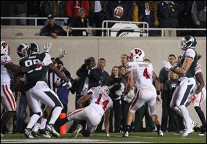 The ball goes up for grabs and into the arms of Michigan State's Keith Nichol, right, after being tipped on a pass on the final play of an NCAA college football game, Saturday, Oct. 22, 2011, in East Lansing, Mich. Also seen are Wisconsin's Marcus Cromartie, 14, Aaron Henry, 7, and Jared Abbrederis, 4, and Michigan State's Dion Sims, 80, and B.J. Cunningham, left rear.