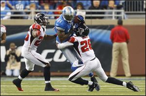 Lions wide receiver Calvin Johnson (81) is tackled by Falcons free safety Thomas DeCoud (28) and defensive back Kelvin Hayden (26) in the second half.