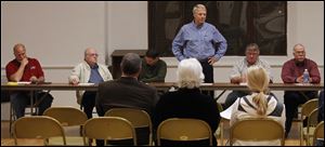 Mayor Lowell Krumnow, left, and his brother James, a councilman, are at opposite ends of the table as Doug Perkins addresses a forum.