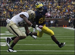 Purdue's Albert Evans covers UM's Fitzgerald Toussaint during first half at Michigan Stadium in Ann Arbor, Mich.