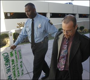 Police Sgt. Harold Mosley leads Occupy Toledo protestor Rick Van Landigham to the public safety building for booking.