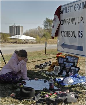 Mckinley Keil, 8, wipes away tears Monday as she looks at a memorial outside the Bartlett Grain Company in Atchison, Kan. Keil's dad, Travis Keli, was one of six people killed in an explosion at the elevator Saturday night. 