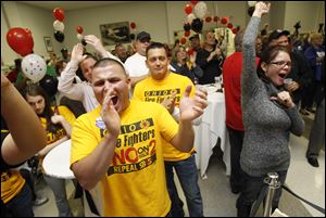 Toledo Fire Dept. Lt. Daniel Brown-Martinez, front left, his brother David Brown, center,and Rachael Lee of Toledo, right, join the crowd celebrating the defeat of State Issue 2 at the Teamsters Hall in Toledo.