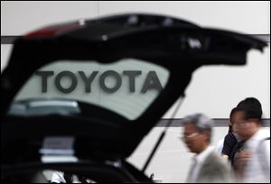 People walk by a car on display at Toyota's Tokyo, Japan, headquarters. 