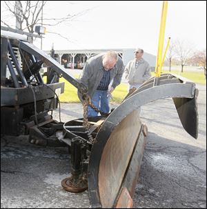 Robert Shirey, equipment manager for the transportation department's Bowling Green district, left, checks connections on a plow. With him Tuesday was Layth Istefan, district highway administrator.
