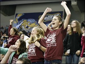 Lindsay Nissen, 11, center, and Ana Rofkar, 11, right, sixth graders at Genoa Middle School, cheer for a Genoa teacher who was participating in an on-ice competition between periods at the Toledo Walleye hockey game against the Chicago Express at the Huntington Center in Toledo.