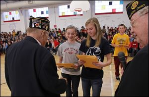 Marine veterans Wesley Falls, left, and Robert Darr accept copies of letters of thanks from eighth graders Carol Wygant, second from left, Keely Pohl, center, and Andrew Headman  after the assembly at McCord Junior High School in Sylvania.