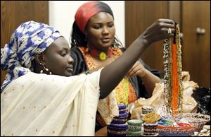 Tanzanian artists Zena Walakai, left, and Maria Chuwa, right, who are studying in Toledo, put their jewelry out for sale during the 