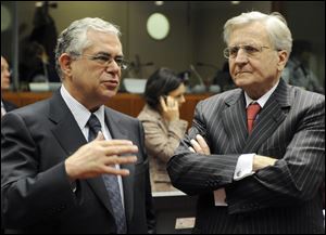 Former European Central Bank President Jean-Claude Trichet, right, shares a few words with former Vice- President of the European Central Bank Lucas Papademos, left, prior to the start of the European Union EcoFin council of ministers meeting in this Dec. 2, 2009 file photo.