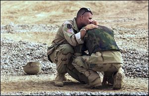 U.S. military police officer Brian Pacholski comforts his hometown friend, U.S. military police David Borell, both from Toledo, Ohio, at the entrance of the military base in Balad, about 50 kilometers (30 miles) northwest of Baghdad, Friday, June 13, 2003. Borell broke down after seeing three Iraqi children who were injured while playing with explosive material.