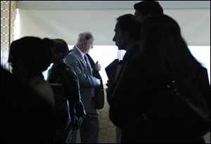 A man pauses by a window as job seekers wait to get information and drop off resumes during a job fair in Boston.