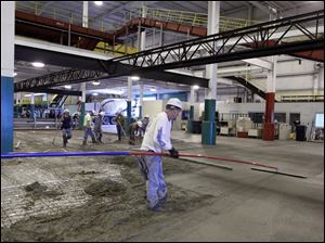 Workers pour concrete in BX Solutions facility at Toledo Express. The renovations are to transform BAX Global, the cargo hub that shut down Sept. 1, to fit the new business geared to trucked freight.