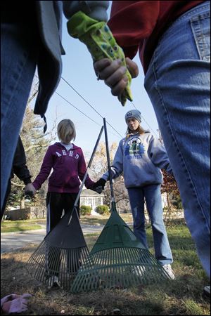 Annie Pirkle, left, and Cassie Arvay, both 12, pray with members of her church group after they raked leaves at 6730 Roosevelt Dr. in Sylvania, Ohio. The kids, from the Sylvania First United Methodist Church, were volunteers for a raking project for the Sylvania Senior Center.