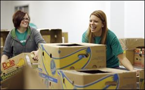 Erin Knopsnider, left, an operations manager, and Alyssa Berndt, a branch manager in Oregon, have a laugh as they and other volunteers from Charter One sort food at the Northwest Ohio Food Bank as part of the companies Carving Out Hunger Program, Tuesday.
